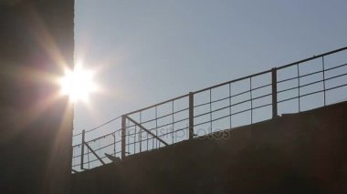 Arka plan. Metal çit güneşin arkasında. Kamera hareketi. Güneş ışınları çit aydınlatmak..