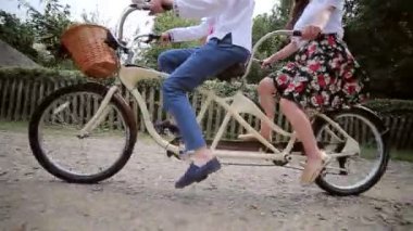 Bir erkek ve bir kadın bir bisiklet tandem sürme close-up. Bacaklar pedal çevir