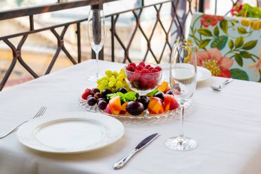 İki kişilik bir masa ile ahududu, üzüm ve Erik meyve tabak açıktır