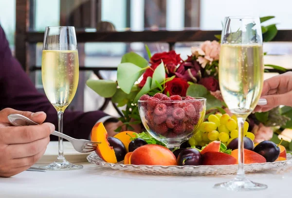 Plaat van fruit met druiven, frambozen en pruimen is op de tafel voor twee. Close-up Stockfoto