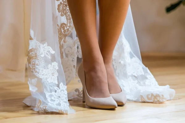 Pernas sexuais da noiva. A noiva está de pé em um chão de madeira, sapato em sapatos de creme, e ela mostra suas belas pernas — Fotografia de Stock