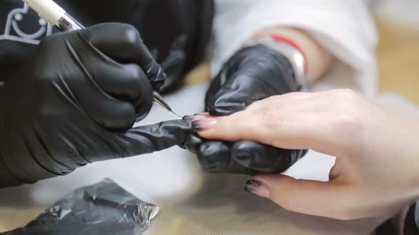 Maestro di manicure, dipinge una manicure per una donna in un salone di bellezza — Video Stock