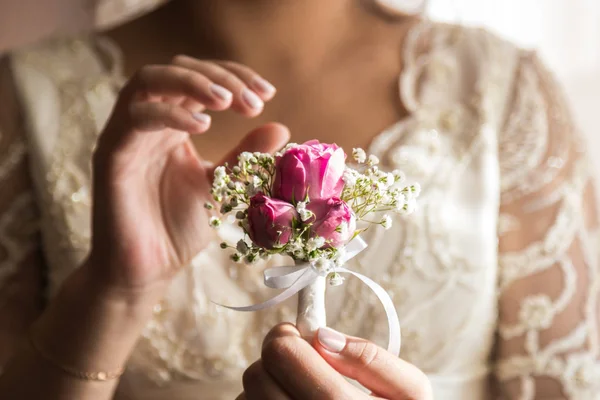 Bruden håller i ett knapphål. Skonsam hand av bruden håller boutonniere för brudgummen — Stockfoto