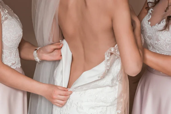Bride with a bare back, wearing a wedding dress, and she shows her sleeve.