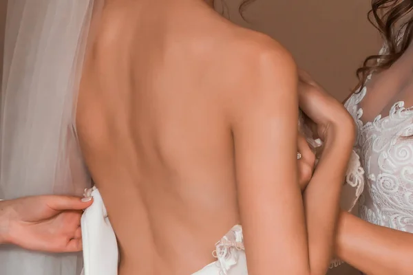 Novia con la espalda desnuda, con un vestido de novia, y ella muestra su manga . — Foto de Stock
