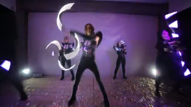 Led show. A team of 5 artists on a stage covered with confetti, skillfully juggles with sticks that glow Led — Stock Video