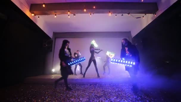 Лідер шоу. Команда з п'яти виконавців на сцені, покрита конфетті, вміло жонглює з паличками, які світяться Led — стокове відео