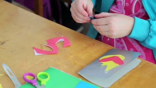 Close-up of a child makes a paper application during a classroom lesson — Stock Video