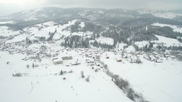 Terbang di atas kota di pegunungan. Salju musim dingin menutupi kota di Carpathians Ukraina — Stok Video
