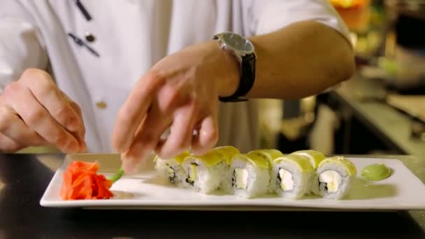 Шеф-повар украшает тарелку ролями суши — стоковое видео