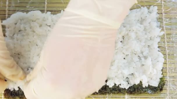 Шеф-повар готовит суши, помещая рис на водоросли Нури. — стоковое видео