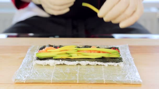 De chef-kok legt op avocado in sushi — Stockvideo