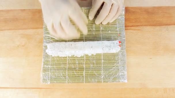 Maestro preparando rollos de sushi usando una estera de bambú y algas nori — Vídeos de Stock