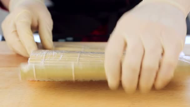 Maestro preparando rollos de sushi usando una estera de bambú y algas nori — Vídeos de Stock