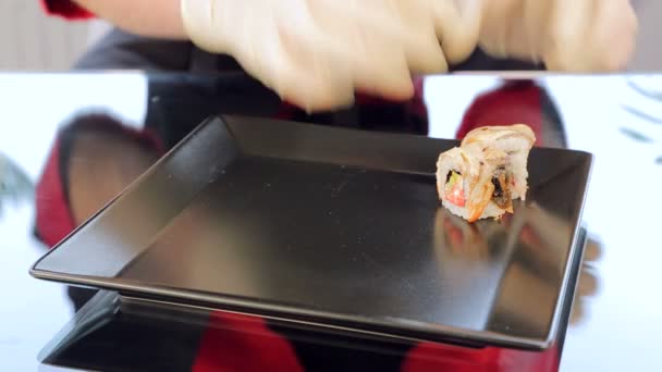 Master sushi rolls puts sushi on a black plate — Stock Video