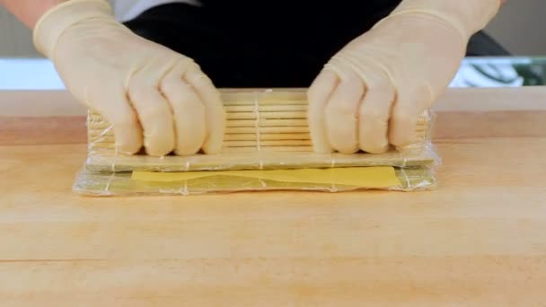 Mester készül Sushi tekercs segítségével egy bambusz mat és nori tengeri moszat