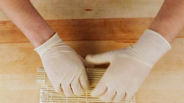 Master preparing Sushi rolls using a bamboo mat and nori seaweed — Stock Video