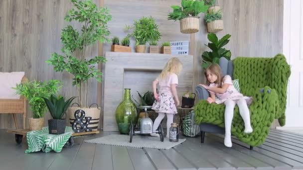 Duas meninas brincando no quarto decorado com plantas verdes. Duas meninas irmãs se divertindo — Vídeo de Stock