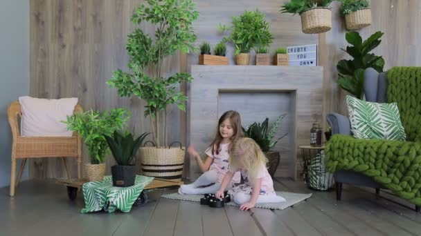 Zwei Mädchen spielen in dem mit grünen Pflanzen dekorierten Raum. zwei Mädchen Schwestern Spaß haben — Stockvideo