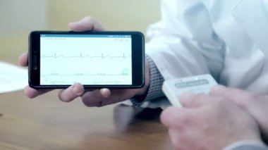 Bir doktor bir kardiyogram cep telefonunda gösterir