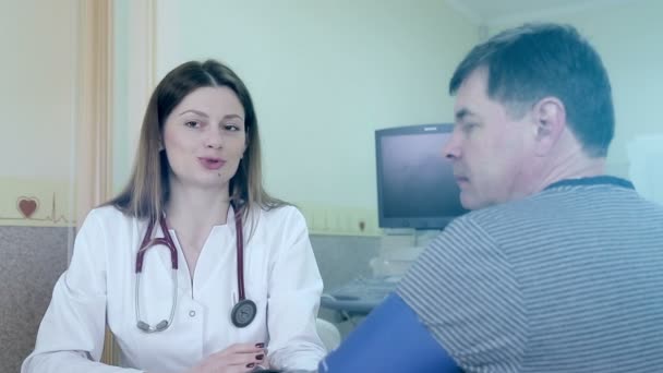 Женщина врач помогает носить сердечно-диагностическое устройство для пациента — стоковое видео