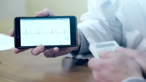 Een arts toont een cardiogram op de mobiele telefoon — Stockvideo