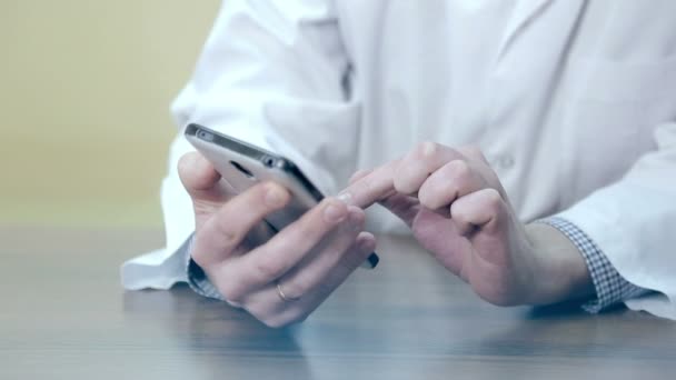 Az orvos használ egy mobil telefon és a tabletta. Egy férfi orvos elektronikus eszközök használata. — Stock videók