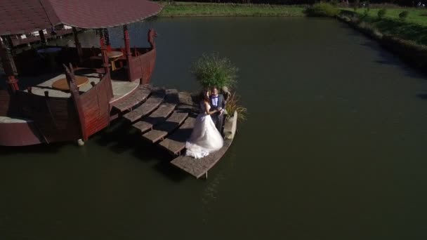 Légifelvételek. Boldog menyasszony egy napsütéses napon a hídon a tónál — Stock videók
