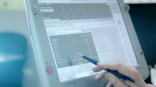 Close-up van een stylus arts voert een computerscherm onderzoek van het hart van de patiënten-patiënt — Stockvideo