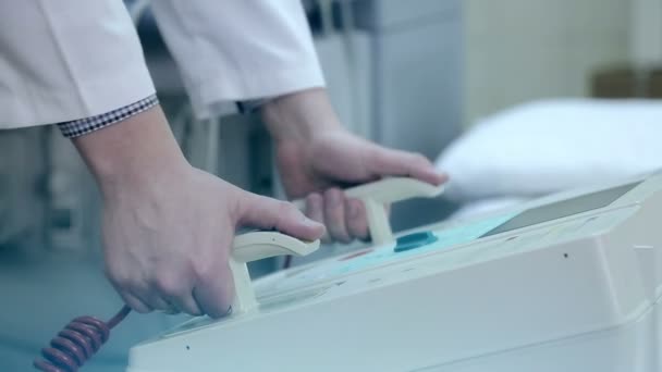De arts neemt de defibrillator in zijn handen en zet de defibrillator in plaats — Stockvideo