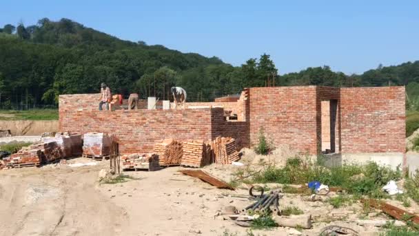 Os trabalhadores constroem uma casa de tijolos vermelhos. Construindo uma casa de tijolo — Vídeo de Stock