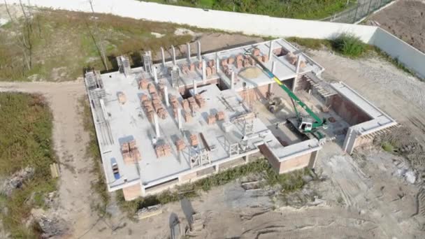 Sobrevolando una casa de ladrillo en construcción. Los trabajadores de la construcción construyen una casa de ladrillo. Nueva casa vista aérea — Vídeos de Stock