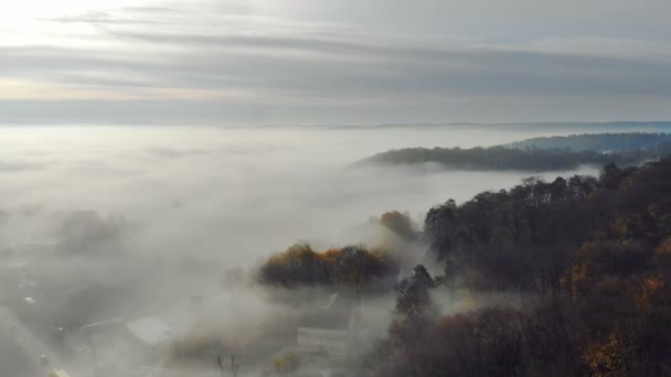 Vliegend over de fantastische ochtendmist boven de stad. De zonsopgang en de gekleurde stralen weerspiegeld in de mist. Fabulous ochtend in de mist gefilmd door drone — Stockvideo