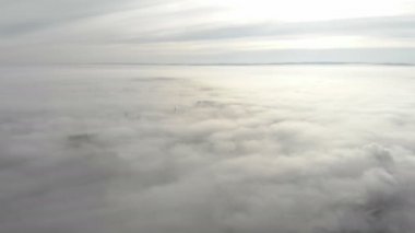 Şehrin üzerinde yoğun sis var. Kamera yokuş yukarı hareket eder ve şehrin üzerine uzanan sisten bir panorama açar..