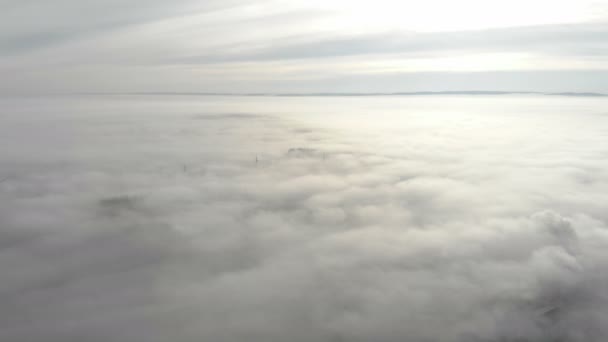 Şehrin üzerinde yoğun sis var. Kamera yokuş yukarı hareket eder ve şehrin üzerine uzanan sisten bir panorama açar.. — Stok video