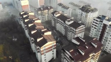 Üstte hava manzarası var. Kanser sisinde evlerin üzerinde uçmak. Sabah sisinde yeni yüksek binalar
