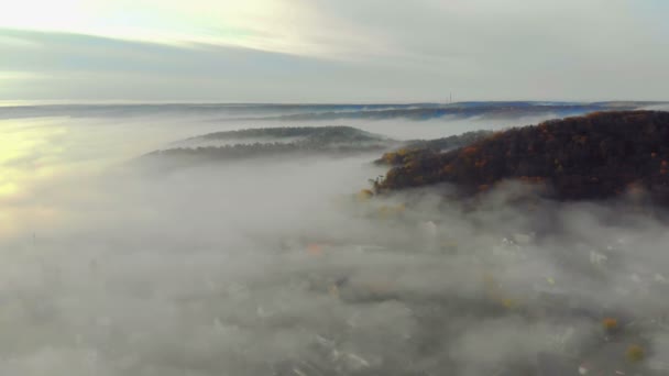 Flygfotografering av berg täckta med tjock morgondimma. Fairy dimma ligger i dalen mellan bergen. Morgonsolen skiner på dimmans yta — Stockvideo