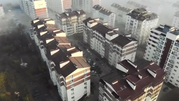 Vista aérea no topo. A sobrevoar casas num nevoeiro oncológico. Novos edifícios altos no nevoeiro da manhã — Vídeo de Stock