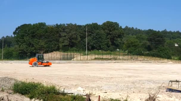 El trabajador de la construcción está conduciendo un rodillo de carretera enorme con espigas y tierra compactada para una fundación grande . — Vídeos de Stock