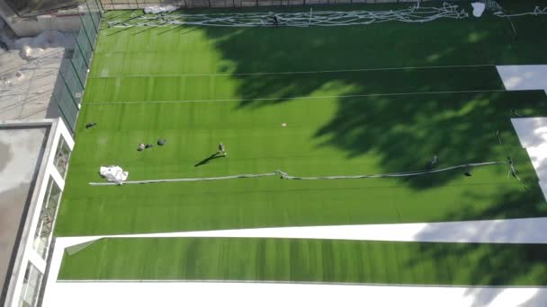 Vista aérea do topo da construção de um campo de futebol. Deitado grama artificial . — Vídeo de Stock