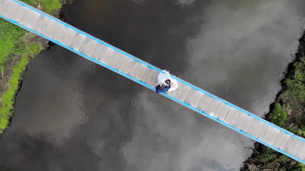 Widok z lotu ptaka Nowożeńcy tańczą taniec na moście nad rzeką. Widok z drona — Wideo stockowe