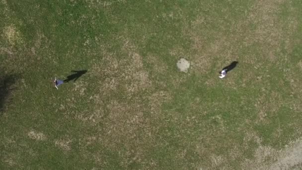 Aerial view on top two young men run across the green grass to each other to exchange and twirl. — Stock Video