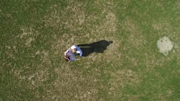 Aerial view on top two young men run across the green grass to each other to exchange and twirl. — ストック動画