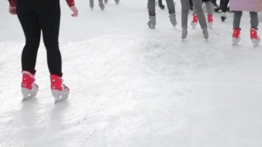 Turistler büyük bir buz pateni pistinde yakın plan kayarlar. Donmuş bir gölde buz pateni yaptıktan sonra ayaklar.
