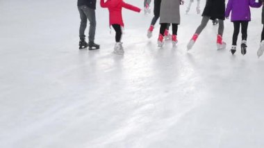 Turistler büyük bir buz pateni pistinde yakın plan kayarlar. Donmuş bir gölde buz pateni yaptıktan sonra ayaklar.