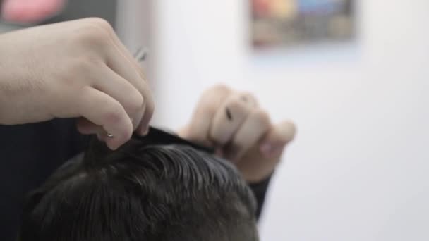 Berber, müşterilerin saçlarını sandalyede kesmek için makas kullanır. Yakın çekim makası saçlarını kesiyor. — Stok video