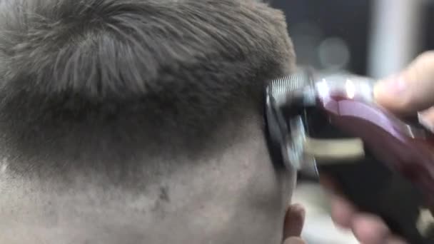 バーバーは、顧客の髪を椅子にカットするためにクリップを使用しています。クローズアップクリップは髪を剃ります — ストック動画
