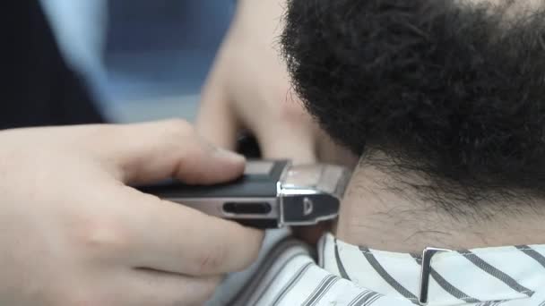 Holič používá střihač na stříhání vlasů klientů v křesle. Detailní střihač oholil vlasy — Stock video