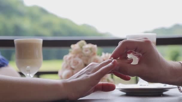 A proposal of marriage. Close-up of a mans hand puts on a gold ring to his beloved and future wife. — 비디오