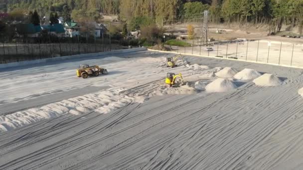 Las excavadoras nivelan el sitio con arena, moviendo arena de los montículos — Vídeos de Stock